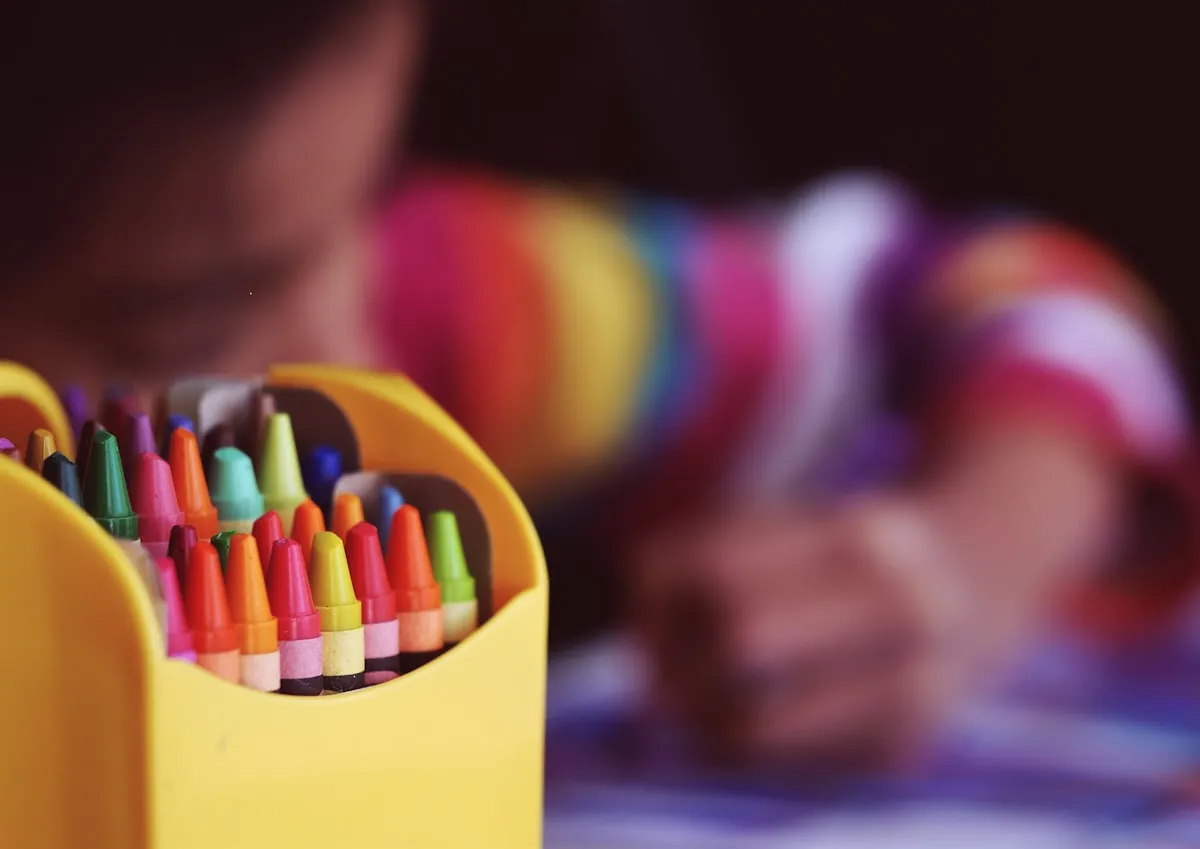 A young child quietly colouring with crayons at a table