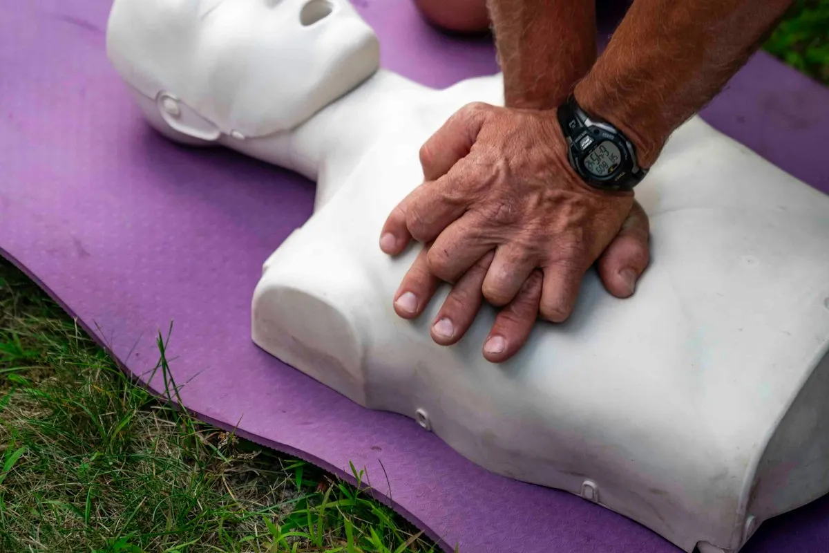 Hands practising chest compressions on a CPR training manikin