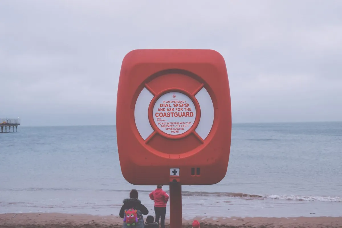 A Coastguard life ring on a British beach with a family by the shore