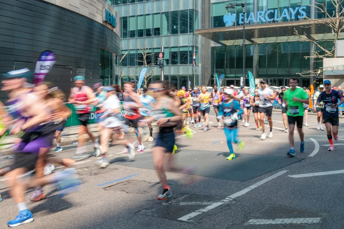 Runners in bright kit taking part in the London Marathon past the towers of Canary Wharf