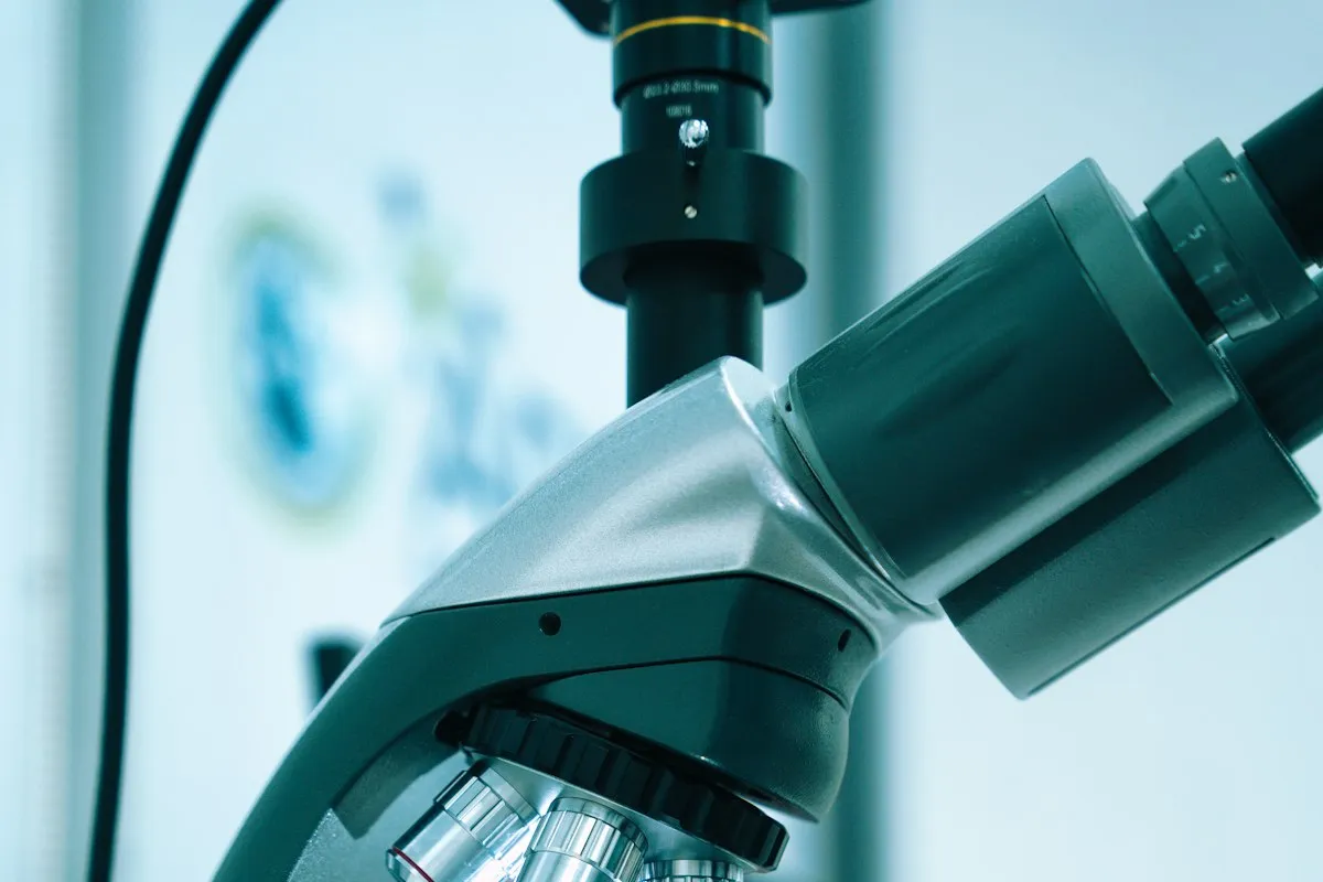 A researcher's gloved hand adjusting a microscope in a laboratory
