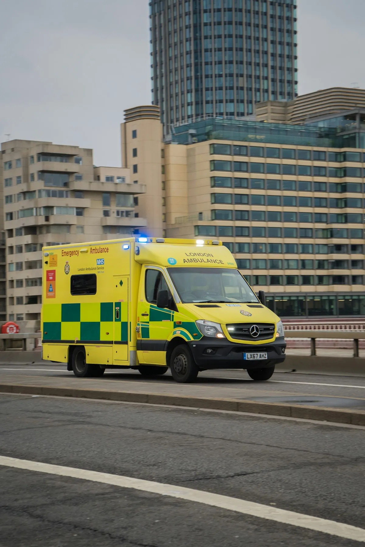 A yellow London Ambulance Service NHS vehicle on a city street