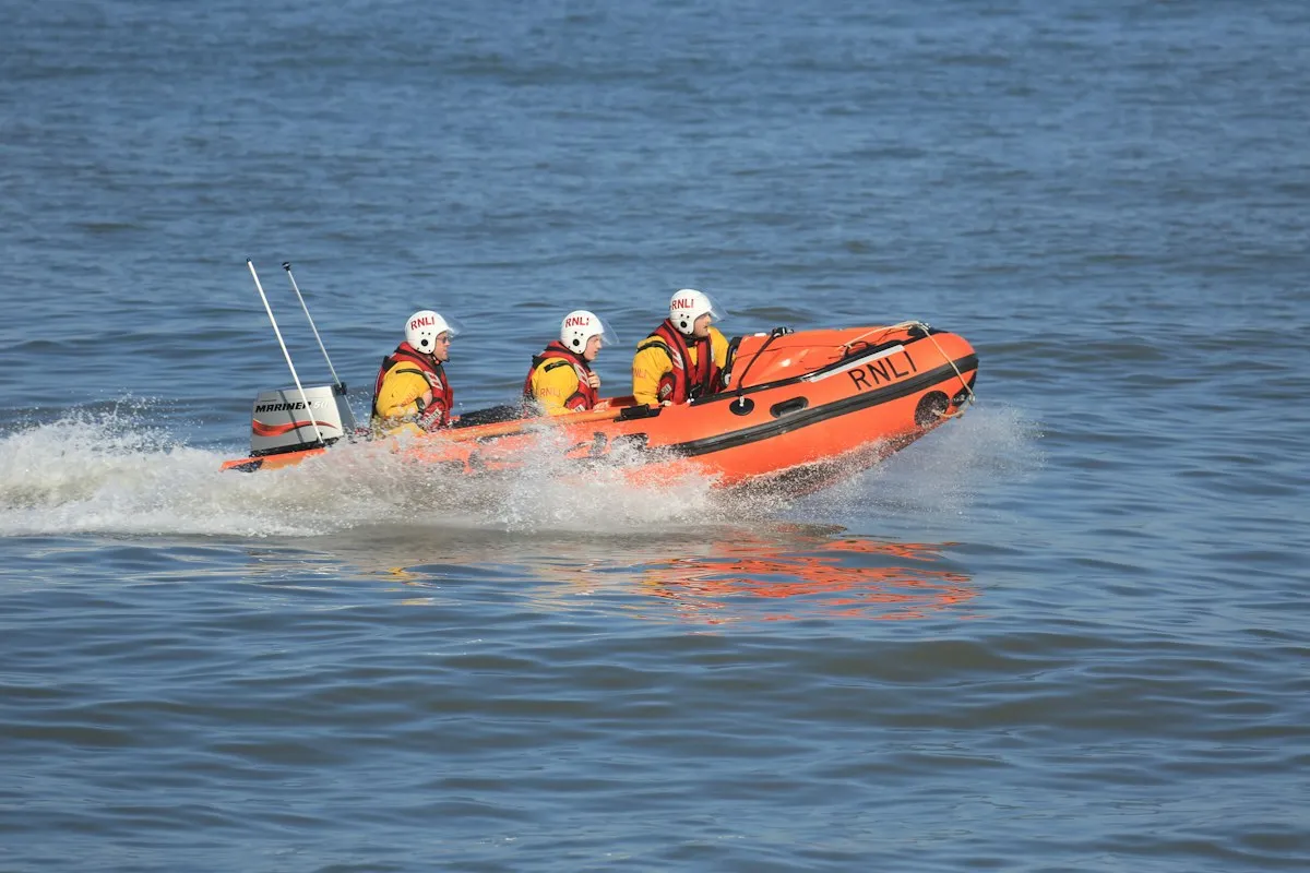 An RNLI inshore lifeboat crew in yellow helmets speeding across the sea