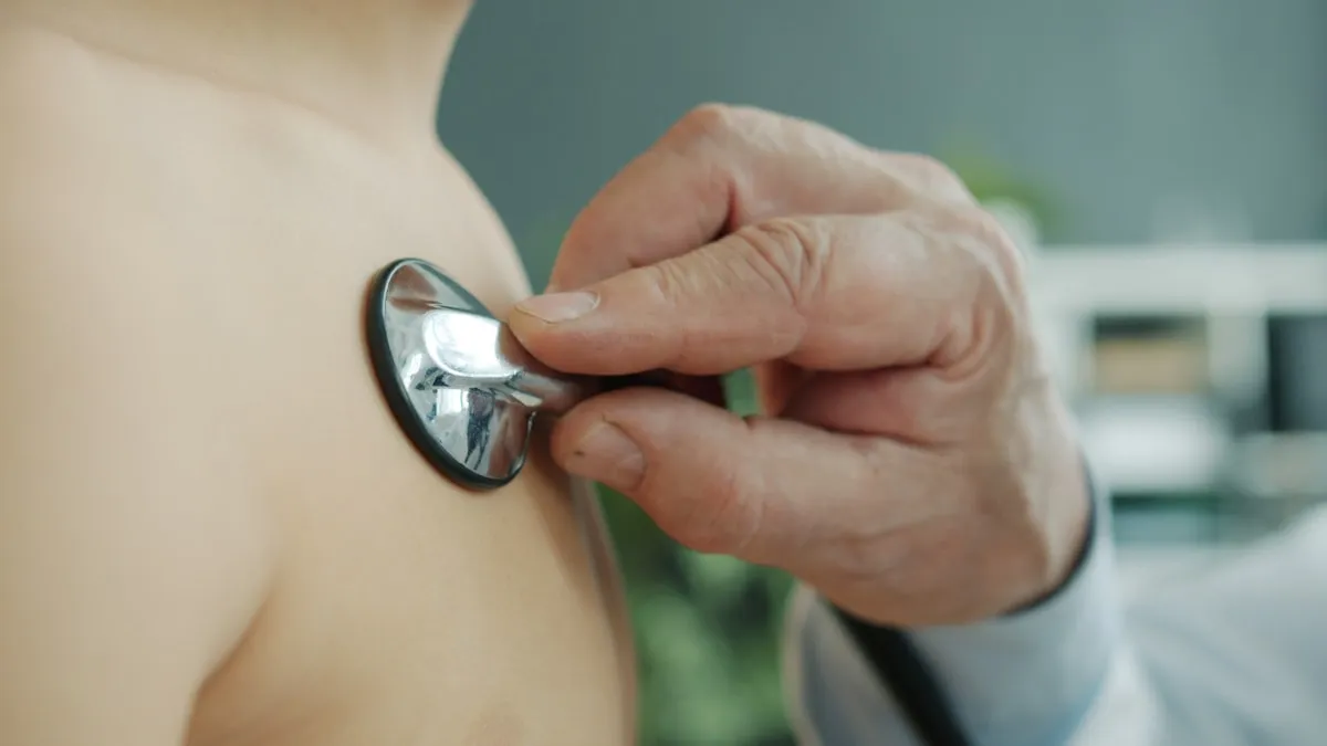 A doctor's gloved hand using a stethoscope to listen to a child's heartbeat during a check-up