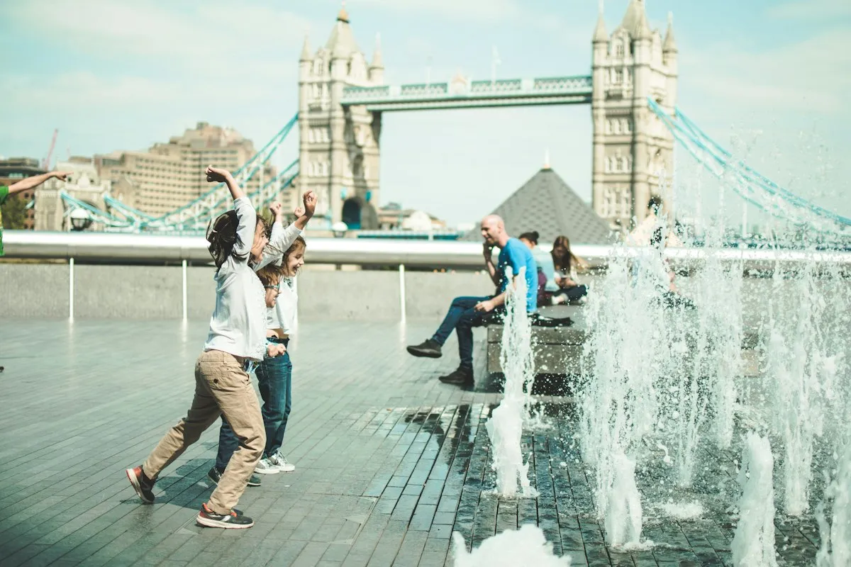 Children dancing in a fountain on the South Bank with Tower Bridge behind them