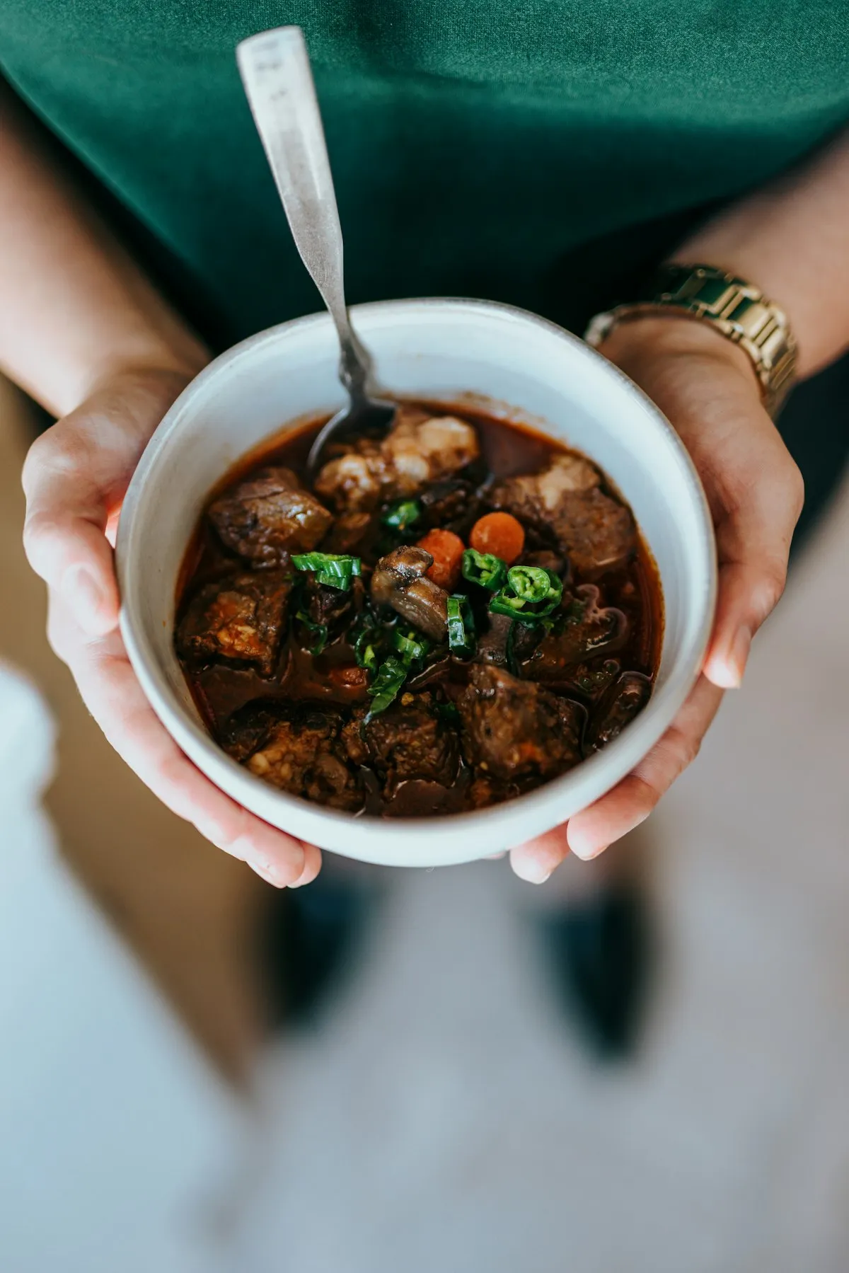 A person cradling a warm bowl of soup in both hands